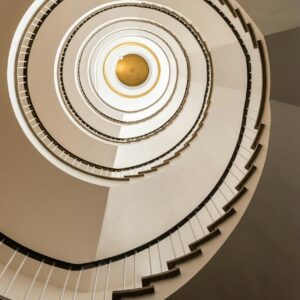 A spiral staircase viewed from below with a gold circular ceiling feature